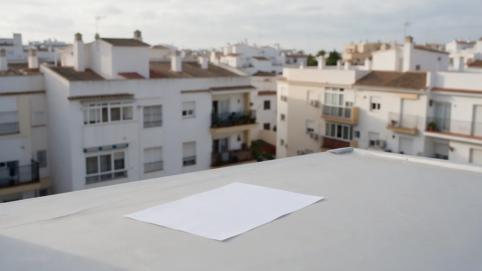 Barrio de bloques de pisos españoles visto desde una azotea con luz de mañana nublada, sin gente
