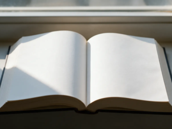 Libro estilo diccionario abierto sobre el alféizar de una ventana con luz de mañana cayendo sobre las páginas en blanco