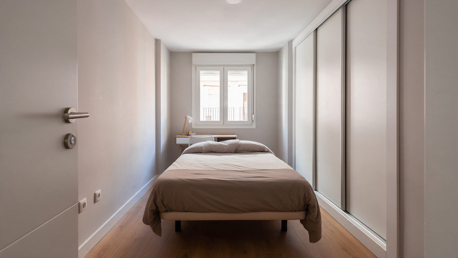 Habitación de 11 metros cuadrados con cama de 135, escritorio bajo la ventana y armario empotrado de puertas correderas