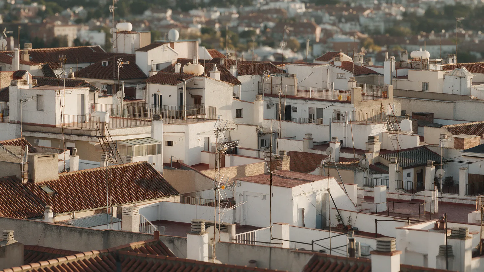 Vista aérea de tejados y bloques de viviendas de Madrid al atardecer, con terrazas y antenas, sin texto visible