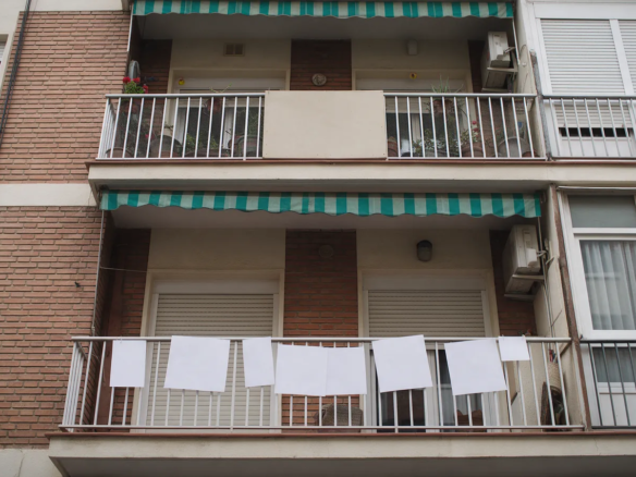 Fachada de un edificio de pisos español con un tablón en blanco en un balcón