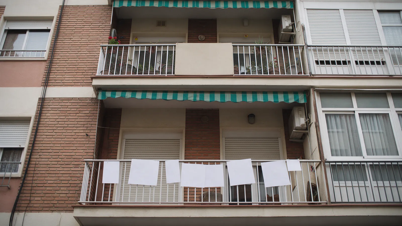 Fachada de un edificio de pisos español con un tablón en blanco en un balcón