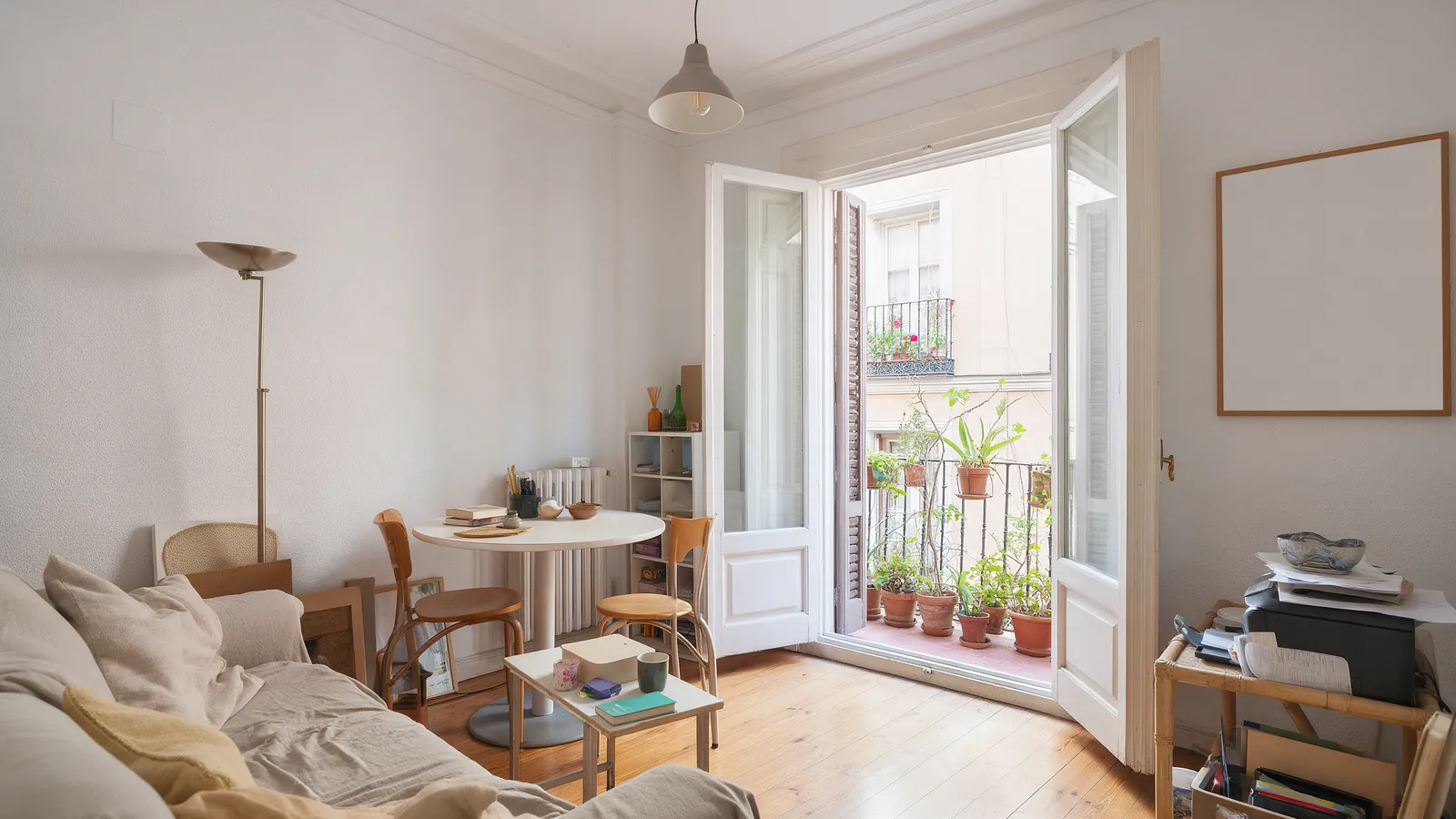 Salón luminoso de un piso habitado con plantas en la terraza visto desde el interior, sin personas
